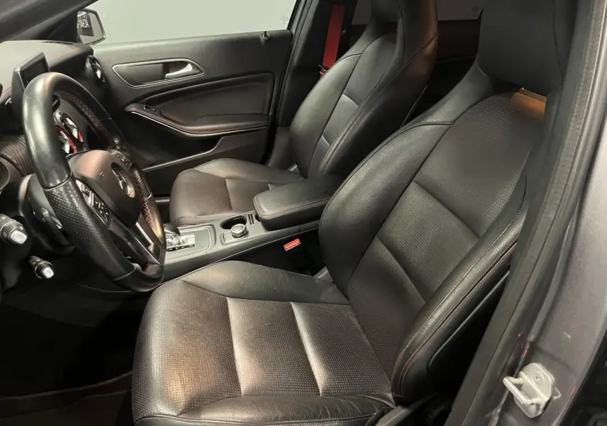 Intérieur avant noir de Mercedes Classe A 45 AMG 2015, sièges sport avec surpiqûres rouges et volant cuir sport.