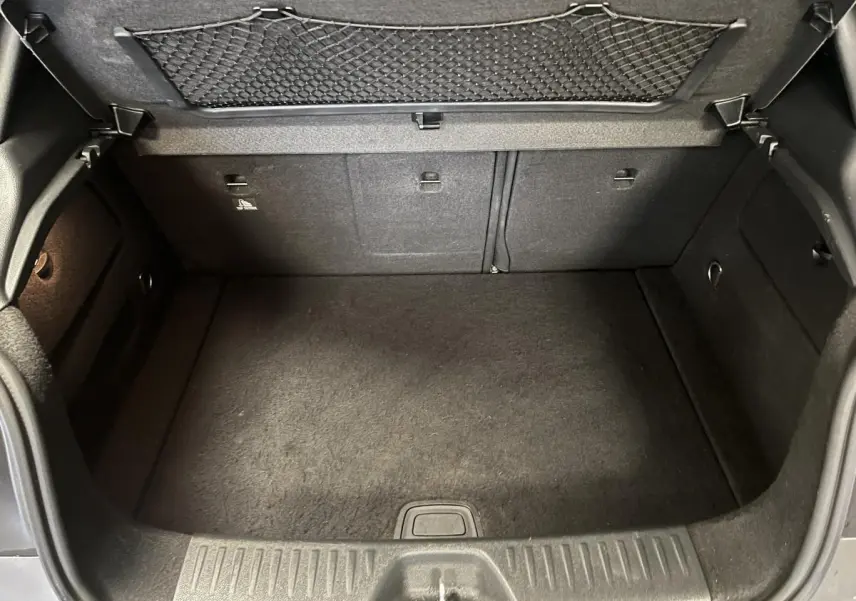 Coffre ouvert de la Mercedes Classe A 45 AMG gris, vue intérieure montrant le tapis et filet de rangement au dos du hayon.