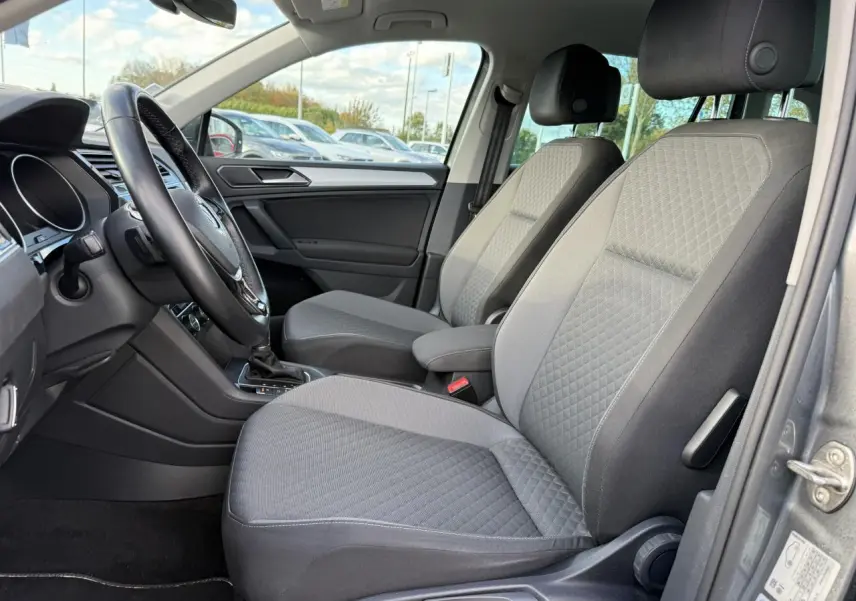 Vue intérieure côté conducteur du Volkswagen Tiguan gris Indium 2018, sièges avant en tissu gris à motif losange.