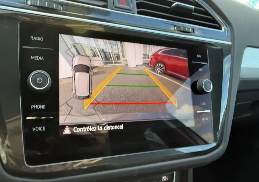 Écran multimédia montrant la caméra de recul du Volkswagen Tiguan gris Indium avec lignes de guidage colorées.