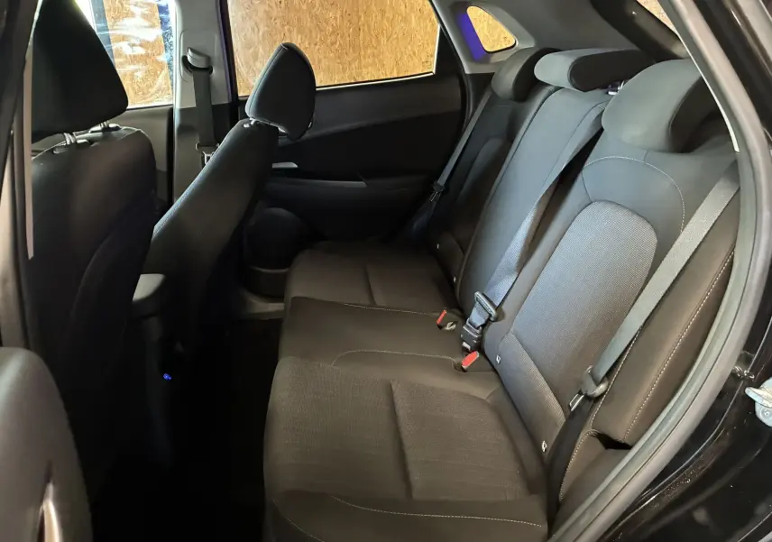 Vue intérieure côté droit des sièges arrière noirs en tissu du Hyundai Kona 2023, avec ceintures de sécurité visibles.