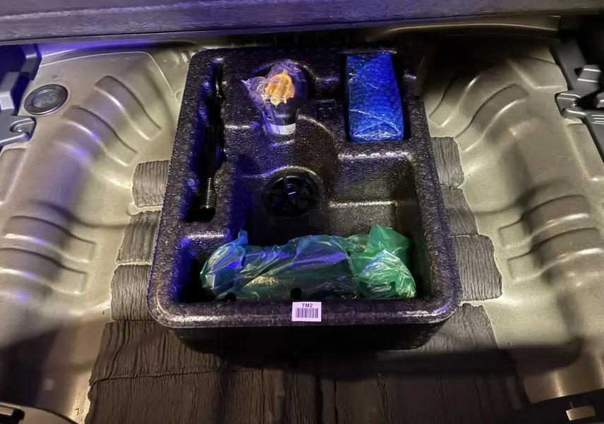 Coffrage de rangement en mousse noire dans le coffre d'un Hyundai Kona 2023 noir, contenant divers accessoires emballés.