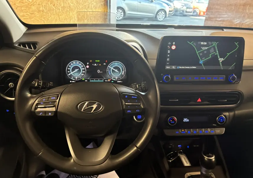 Vue intérieure du tableau de bord du Hyundai Kona 2023 noir, avec volant multifonction et écran tactile GPS lumineux.