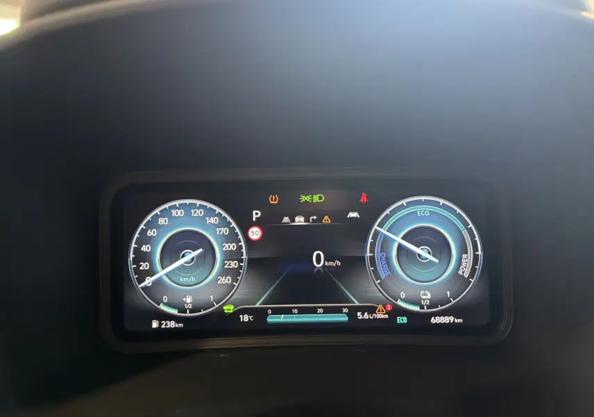 Tableau de bord numérique du Hyundai Kona 2023 affichant la vitesse à 0 km/h et indicateurs hybrides en bleu et blanc.