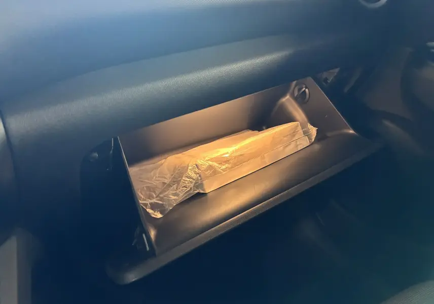 Gant de boîte à gants ouvert côté passager du Hyundai Kona noir 2023, montrant un manuel emballé à l'intérieur.