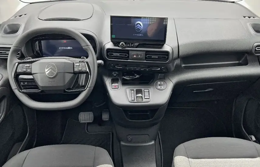 Vue intérieure avant du tableau de bord et du volant noir du Citroën Berlingo Multispace gris, avec écran tactile central allumé.