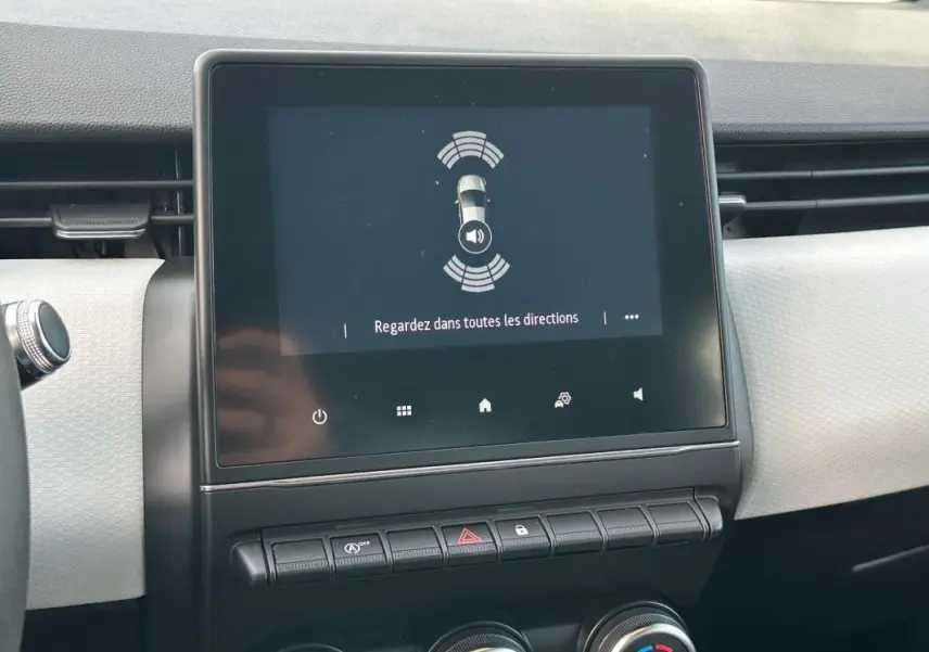 Écran tactile central affichant l'aide au stationnement dans l'habitacle clair d'une Renault Clio V noire.