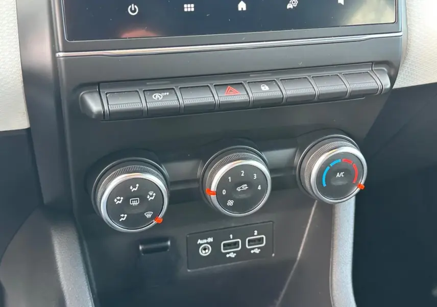 Gros plan sur les commandes de climatisation manuelle et les ports USB de la Renault Clio V SCe 65 Limited noire de 2021.