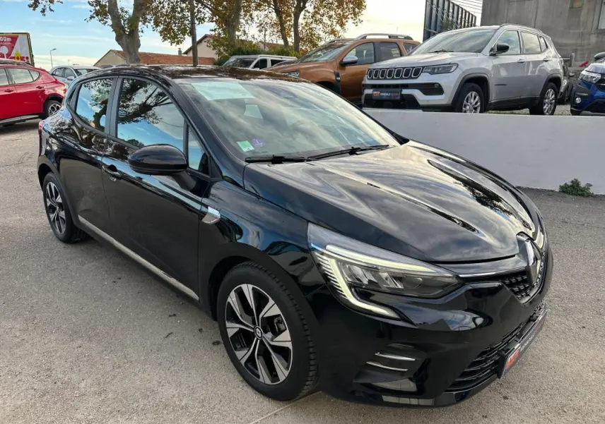 Renault Clio V SCe 65 noir en 3/4 avant droit, avec jantes alliage 16 pouces et feux LED allumés.