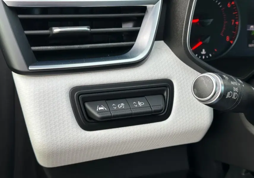 Gros plan sur les commandes d'aide à la conduite à gauche du volant dans l'habitacle clair d'une Renault Clio noire 2021.