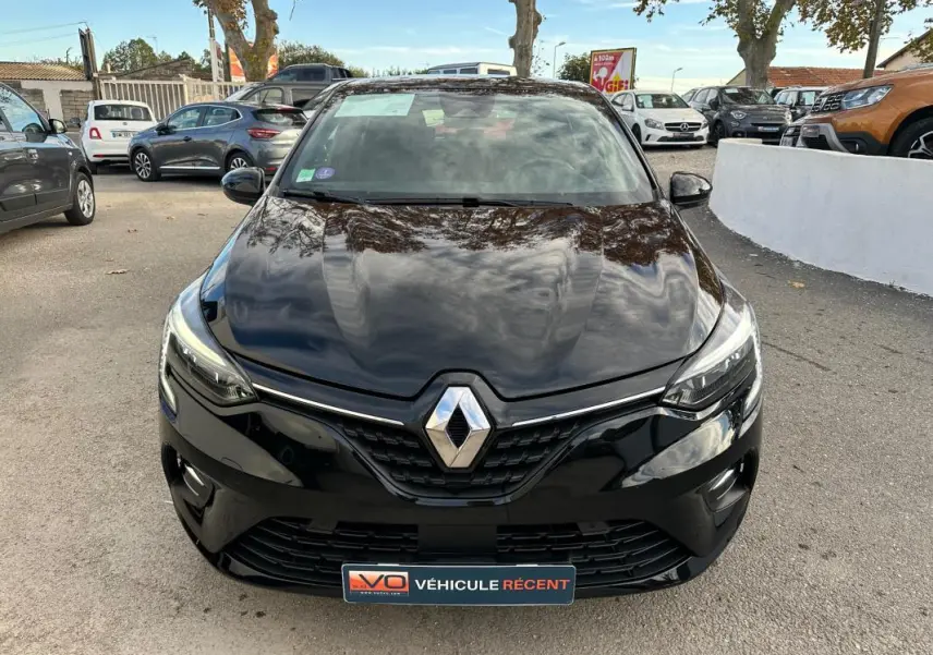 Vue frontale d'une Renault Clio V SCe 65 Limited noire, avec phares allumés et calandre chromée visible.