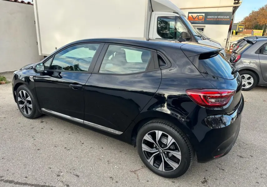 Vue 3/4 arrière droite d'une Renault Clio V SCe 65 noire avec jantes alliage 16 pouces stationnée en extérieur.