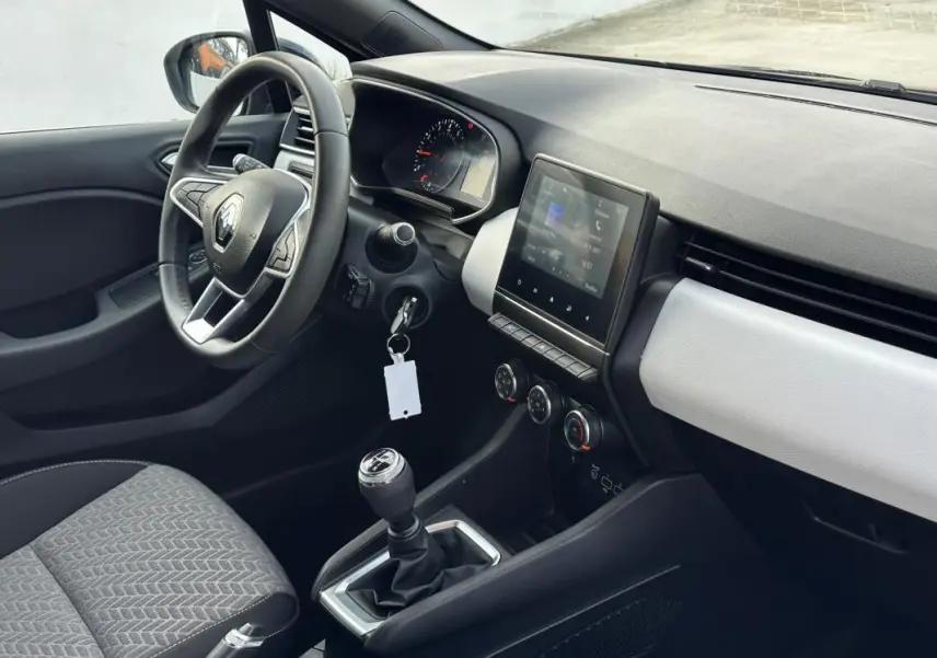 Vue intérieure côté conducteur de la Renault Clio V SCe 65 21 Limited avec volant, écran tactile et levier de vitesse manuel.