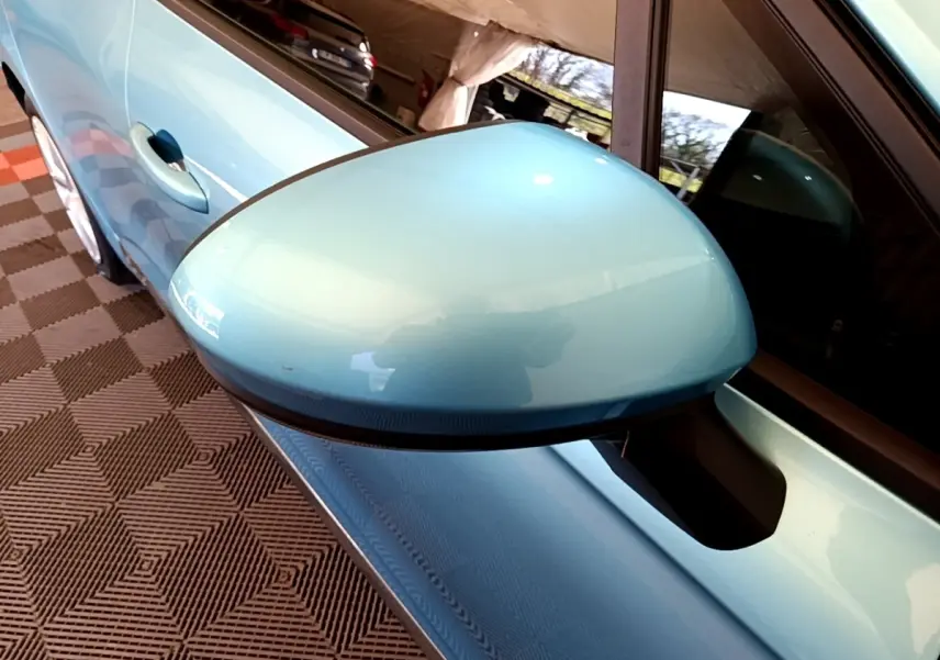 Gros plan sur le rétroviseur côté conducteur bleu clair d'une Renault Clio Business E-Tech hybride 2021, avec poignée de porte visible.