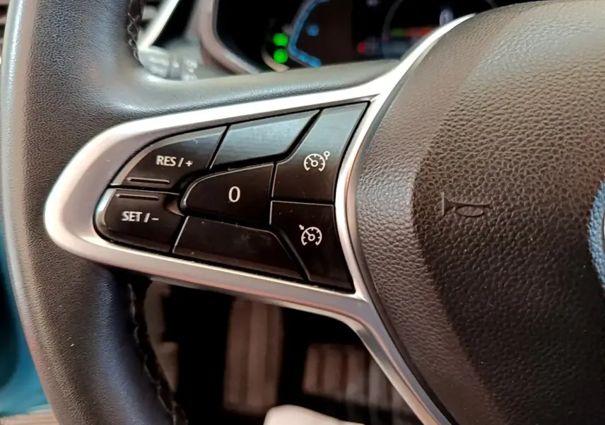 Gros plan sur les commandes du régulateur de vitesse au volant en cuir synthétique de la Renault Clio Business E-Tech hybride bleu.