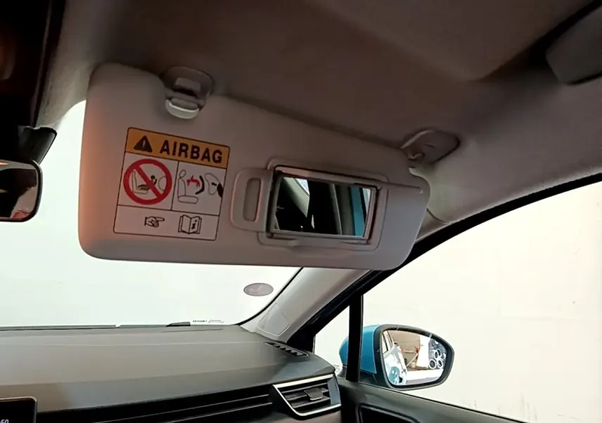 Vue intérieure côté passager de la Renault Clio Business E-Tech hybride bleu, avec pare-soleil ouvert et rétroviseur latéral visible.