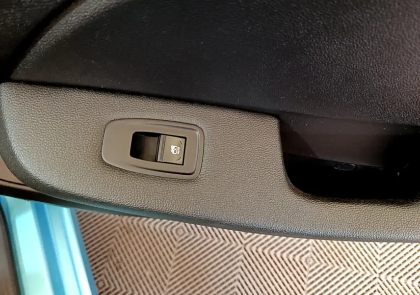 Gros plan sur le bouton de commande de la vitre électrique côté porte intérieure d’une Renault Clio Business E-Tech hybride bleu.