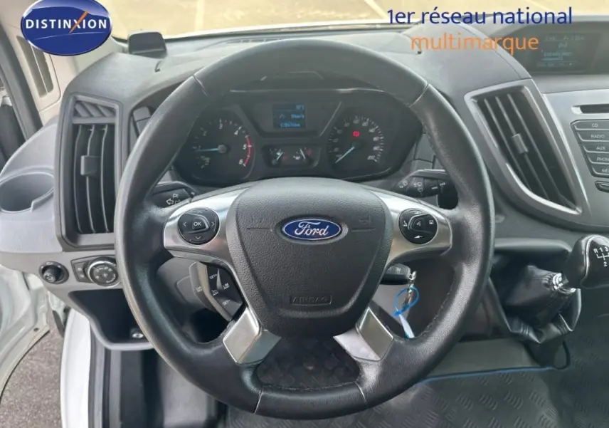 Vue intérieure centrée sur le volant noir du Ford Transit Fourgon blanc, avec levier de vitesses manuel visible à droite.