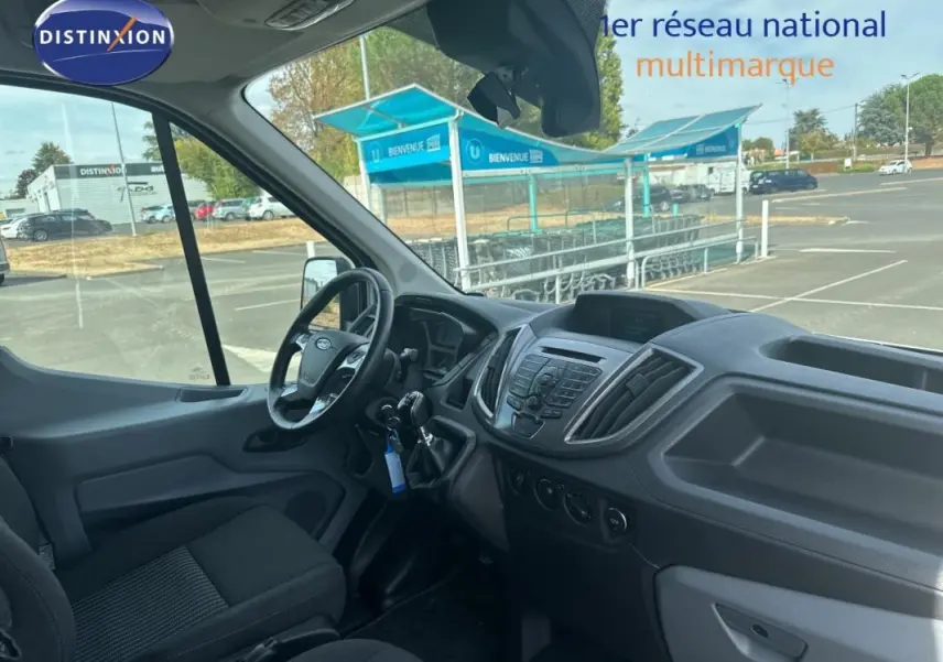 Vue intérieure côté conducteur du Ford Transit Fourgon blanc, montrant le tableau de bord et le volant.