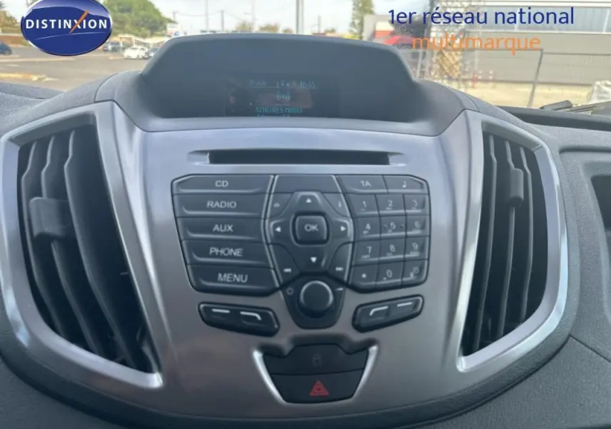Vue rapprochée du tableau de bord gris du Ford Transit Fourgon blanc, mettant en valeur la console centrale avec commandes audio.