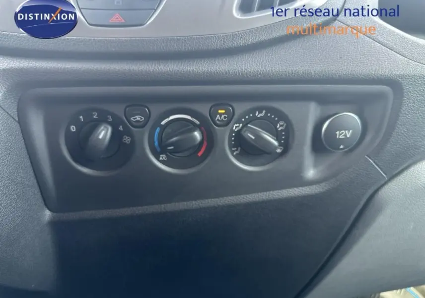 Tableau de bord du Ford Transit Fourgon blanc 2015, vue rapprochée des commandes de climatisation et prise 12V.