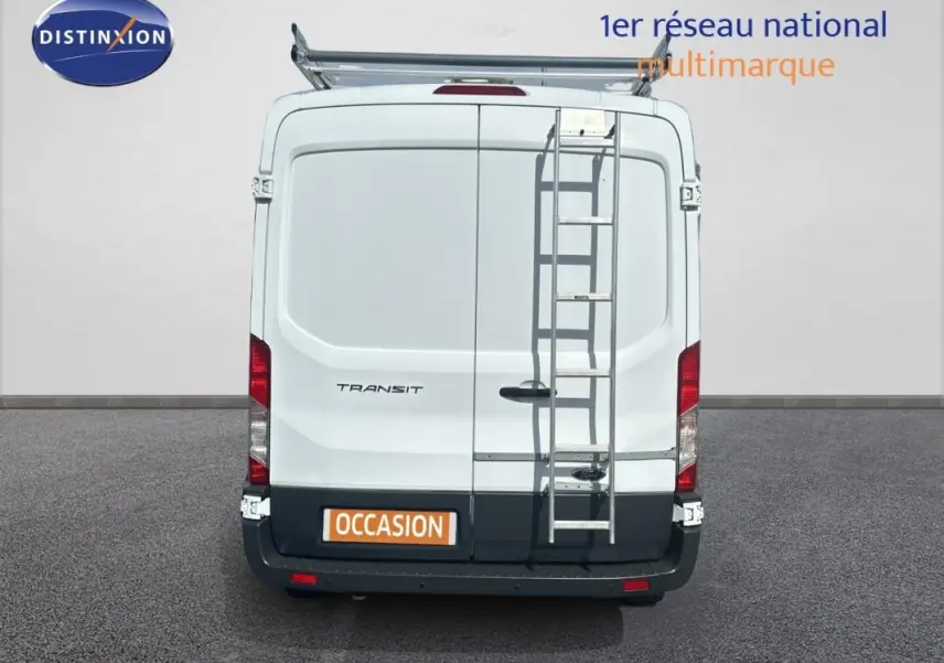 Vue arrière d’un Ford Transit Fourgon blanc 2015 avec échelle métallique fixée et porte latérale visible.