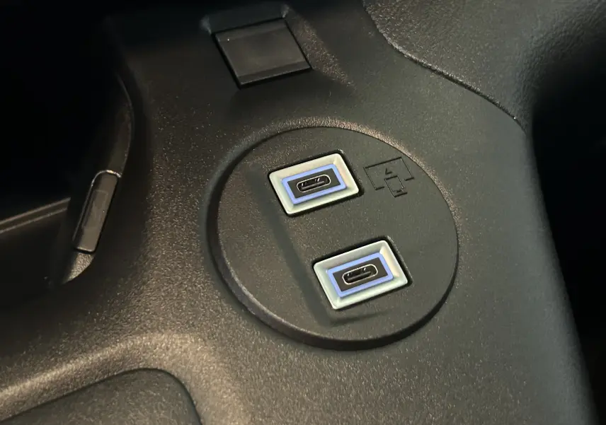 Gros plan sur deux ports USB-C encadrés de bleu intégrés dans la console centrale noire du Citroën Berlingo Multispace 2025.
