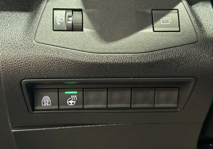 Gros plan sur les commandes noires du tableau de bord du Citroën Berlingo Multispace gris, avec bouton de chauffage de volant allumé.