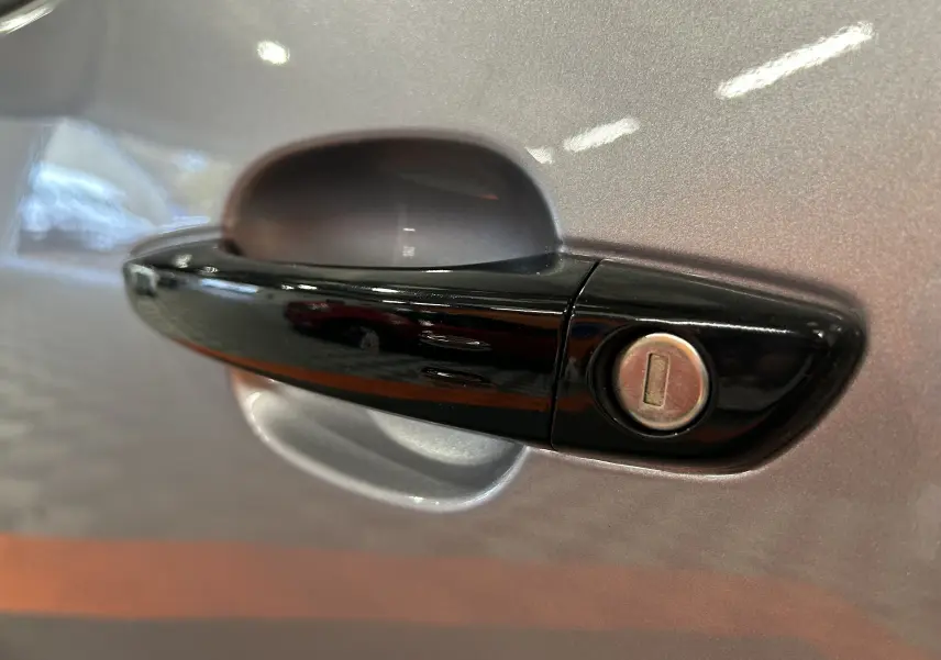 Poignée de porte noire avec serrure sur la portière gris artense côté gauche d'un Citroën Berlingo Multispace 2025.