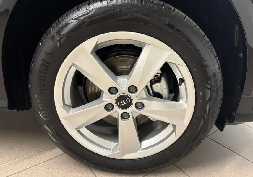 Gros plan sur la roue avant droite d’un Audi Q2 Noir Mythic avec jante argentée à cinq branches.