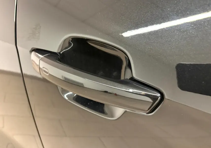 Poignée de porte chromée sur la portière avant gauche d’un Audi Q2 Noir Mythic 2026, finition S Line.