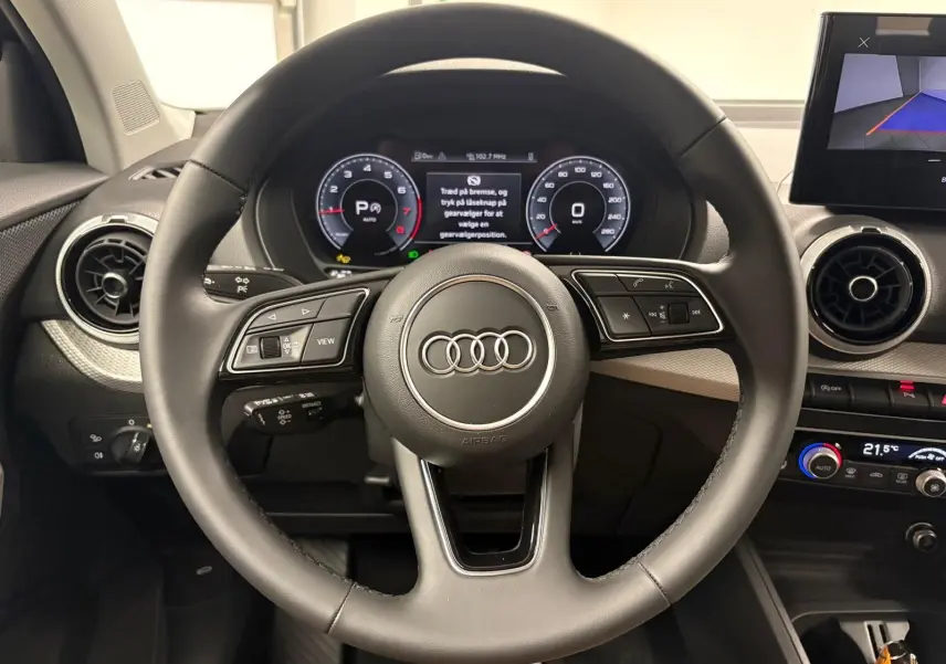 Vue rapprochée du volant multifonction de l’Audi Q2 35 TFSI S Line 2026 avec tableau de bord numérique.