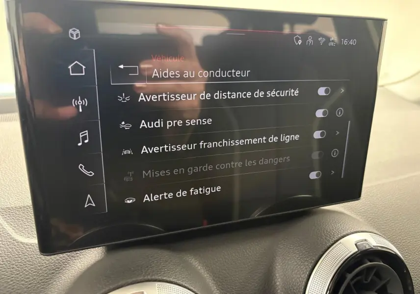 Écran central tactile affichant les aides au conducteur dans l’habitacle d’un Audi Q2 Noir Mythic, vue de face.