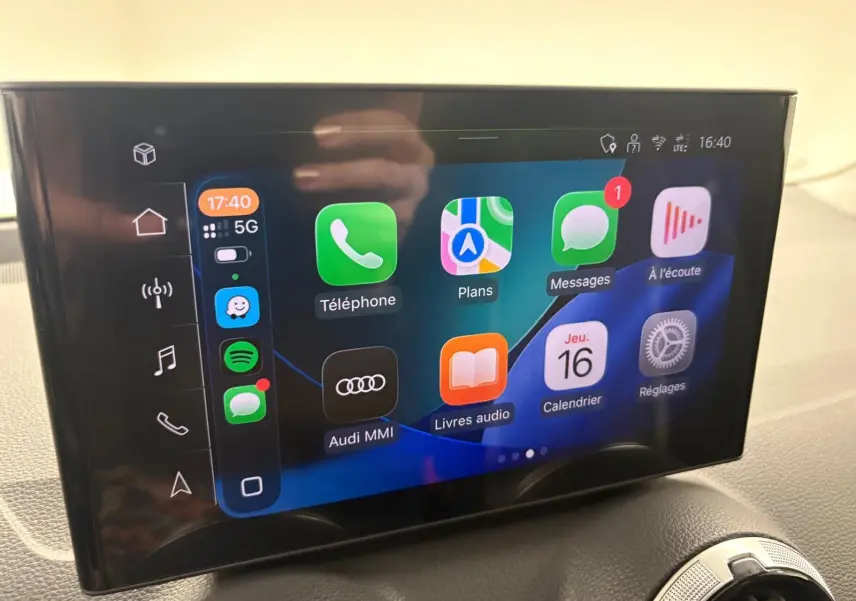 Écran tactile central de l'Audi Q2 35 TFSI 2026 affichant les applications connectées, avec tableau de bord noir en arrière-plan.