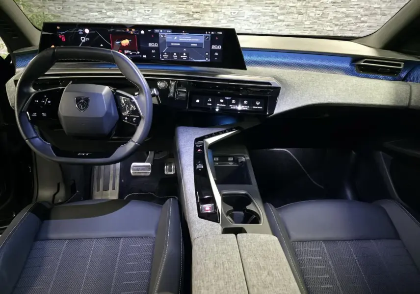 Vue intérieure avant du Peugeot 3008 2025 noir, tableau de bord avec écran panoramique et volant compact GT.