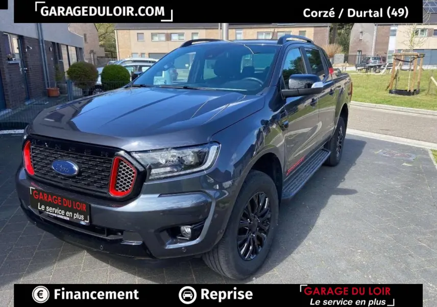 Ford Ranger gris foncé en 3/4 avant droit, avec calandre noire et accents rouges distinctifs.