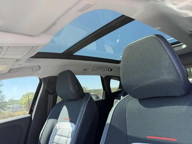 Vue intérieure du Citroën C5 Aircross 2026 montrant les sièges avant en tissu bleu avec toit panoramique vitré.