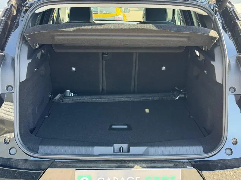 Coffre ouvert vu de l'arrière d'un Citroën C5 Aircross noir Perla Nera, espace de chargement vide et tapis noir.