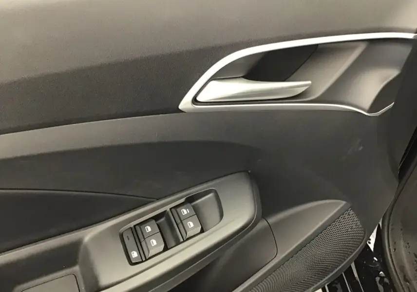 Détail de la porte côté conducteur de la MG3 1.5 Hybrid+ 195 Luxury en Pebble Black, avec commandes de vitres et poignée argentée.