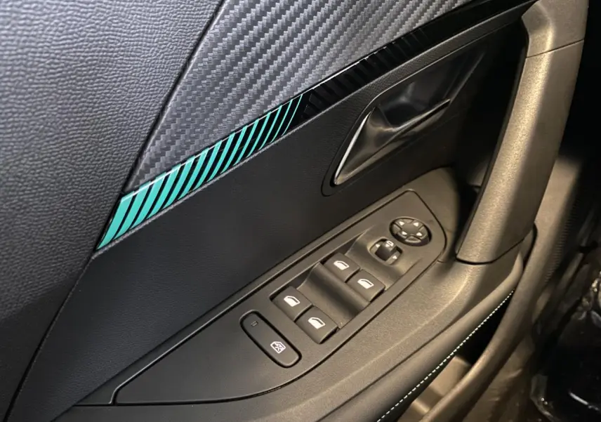 Détail de la porte côté gauche du Peugeot 2008 e-136 Allure Pack 2022 avec insert décoratif bleu et commandes de vitres électriques.
