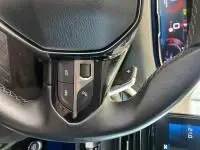 Gros plan sur les commandes audio au volant cuir du Peugeot 5008 bleu célèbes, avec écran tactile en arrière-plan.