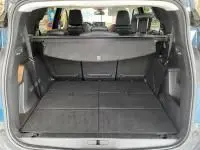 Vue arrière ouverte du coffre spacieux du Peugeot 5008 bleu célèbes, montrant la banquette arrière rabattable et le cache-bagages.