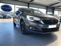 Vue 3/4 avant gauche d'une DS4 gris Platinium 2017 en showroom, soulignant ses phares LED et jantes noires distinctives.
