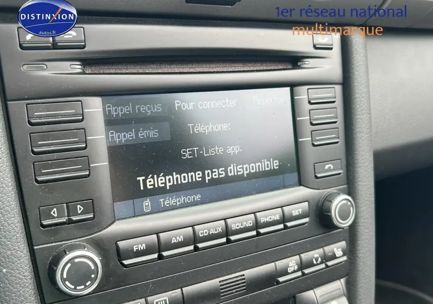 Gros plan sur l'écran multimédia et la console centrale noire d'une Porsche Boxster 987 2.9 PDK de 2012.