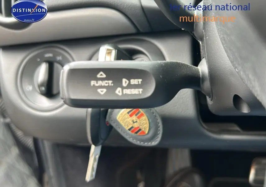 Gros plan sur la commande de régulateur de vitesse et la clé Porsche dans l'habitacle noir d'une Boxster 987.