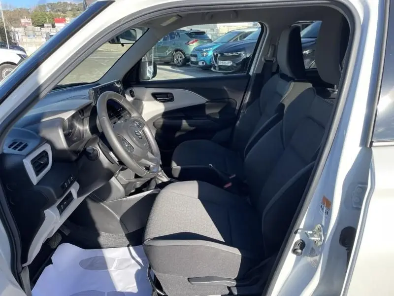 Intérieur de la Suzuki Swift 1.2 Hybrid 2025 vue côté conducteur, sièges tissu gris et tableau de bord moderne.