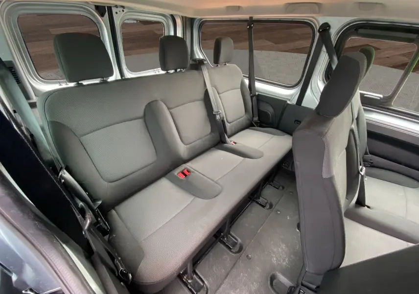Vue intérieure latérale droite du Renault Trafic Combi gris platine 2023, montrant les sièges tissu noir pour 9 places.