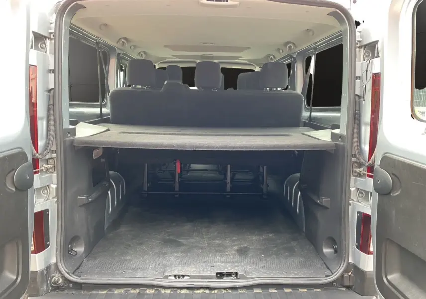 Vue arrière ouverte du Renault Trafic Combi gris platine 2023, montrant l'espace de chargement et les sièges arrière.