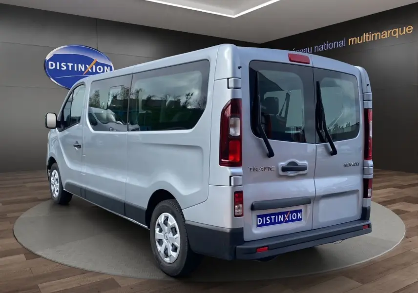 Vue 3/4 arrière droite d’un Renault Trafic Combi gris platine 2023 avec portes arrière vitrées et jantes acier.