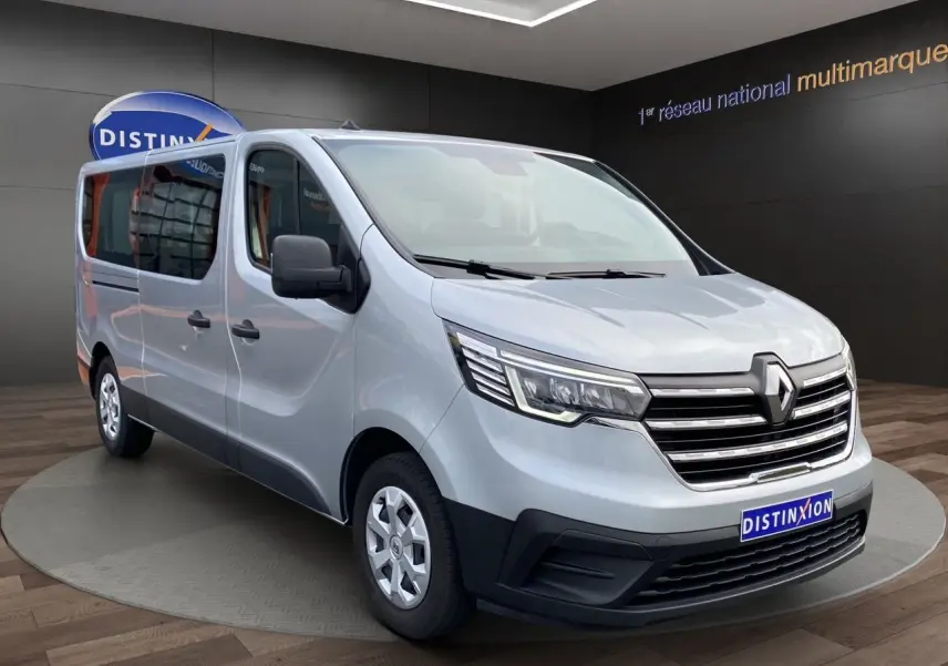 Vue 3/4 avant gauche d’un Renault Trafic Combi gris platine 2023, grand utilitaire neuf avec calandre chromée.